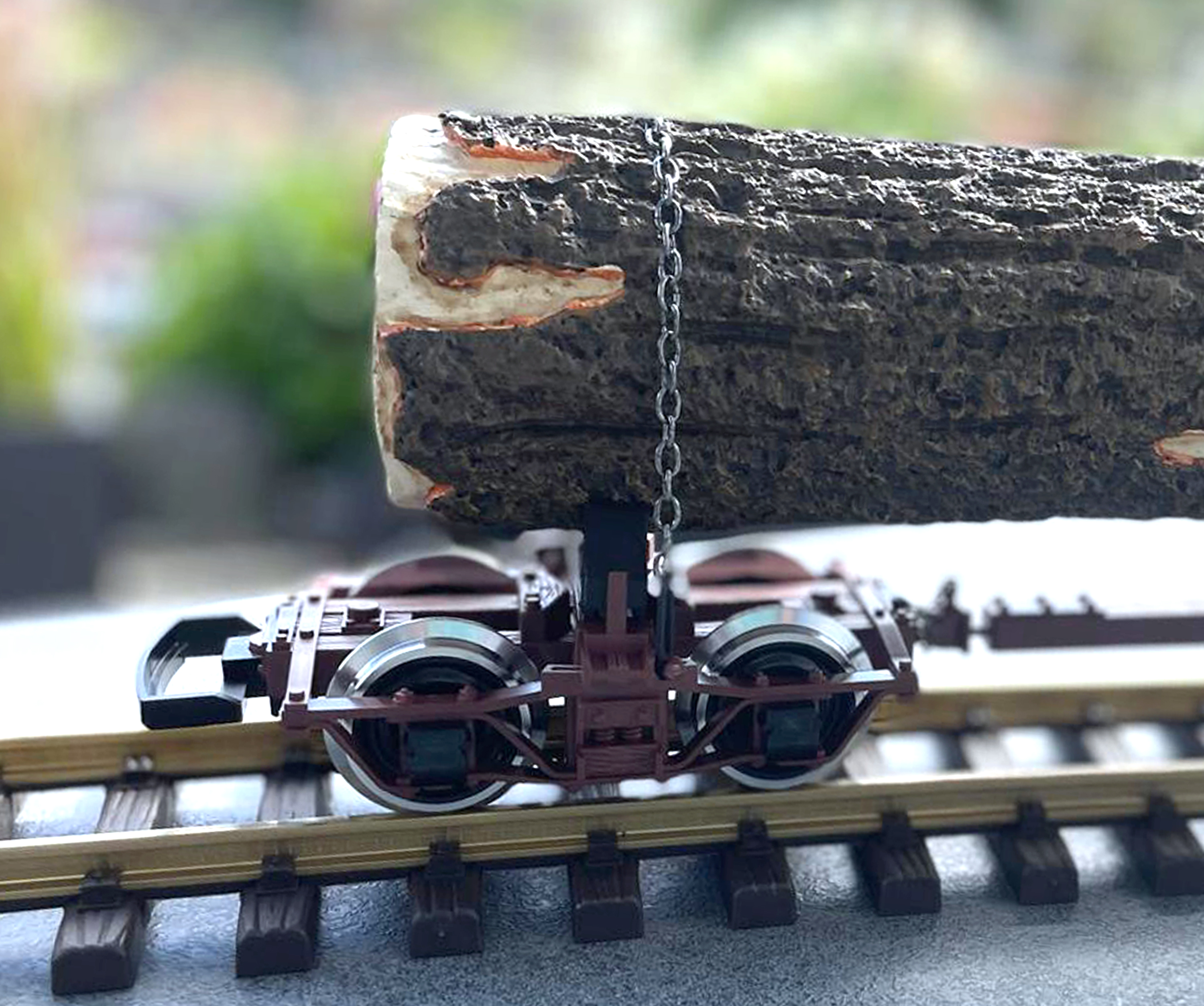 Detailaufnahme eines kurzen Holztransportwagens mit dem mchtigen Baumstamm und der Sicherung durch eine Kette. 