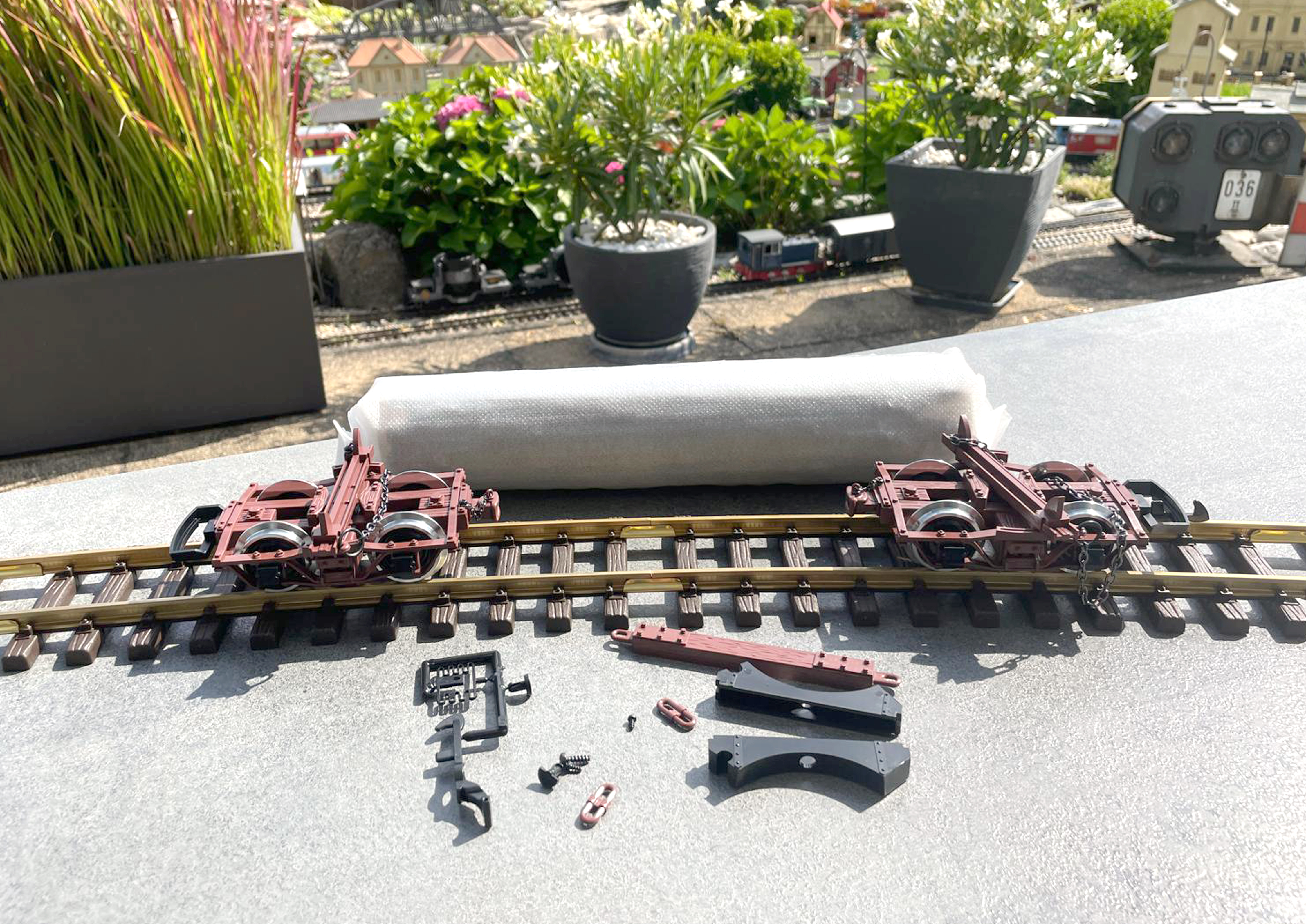 Aus dem zweiteiligen Kunststoffinnenteil herausgehoben: die beiden braunen kurzen Holztransportwagen (Trucks) von US Bahngesellschaften - der noch verpackte Baumstamm - die zweite Kupplung - der Abstandsbalken - die beiden Auflagen fr den Stamm - zwei LINKS zum kurz kuppeln - drei Schrauben. Auf dem Bild fehlt noch die Ersatzteilliste die jedoch auch auf der LGB WEB Seite zum Download bereit steht.