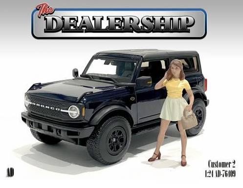 American Diorama - Art. Nr. 76409, Kundin II - bekommt die junge Frau den SUV gekauft? Eine gute Figur macht die Dame im kurzen Rock mit gelbem Shirt neben dem abgebildeten Auto. 