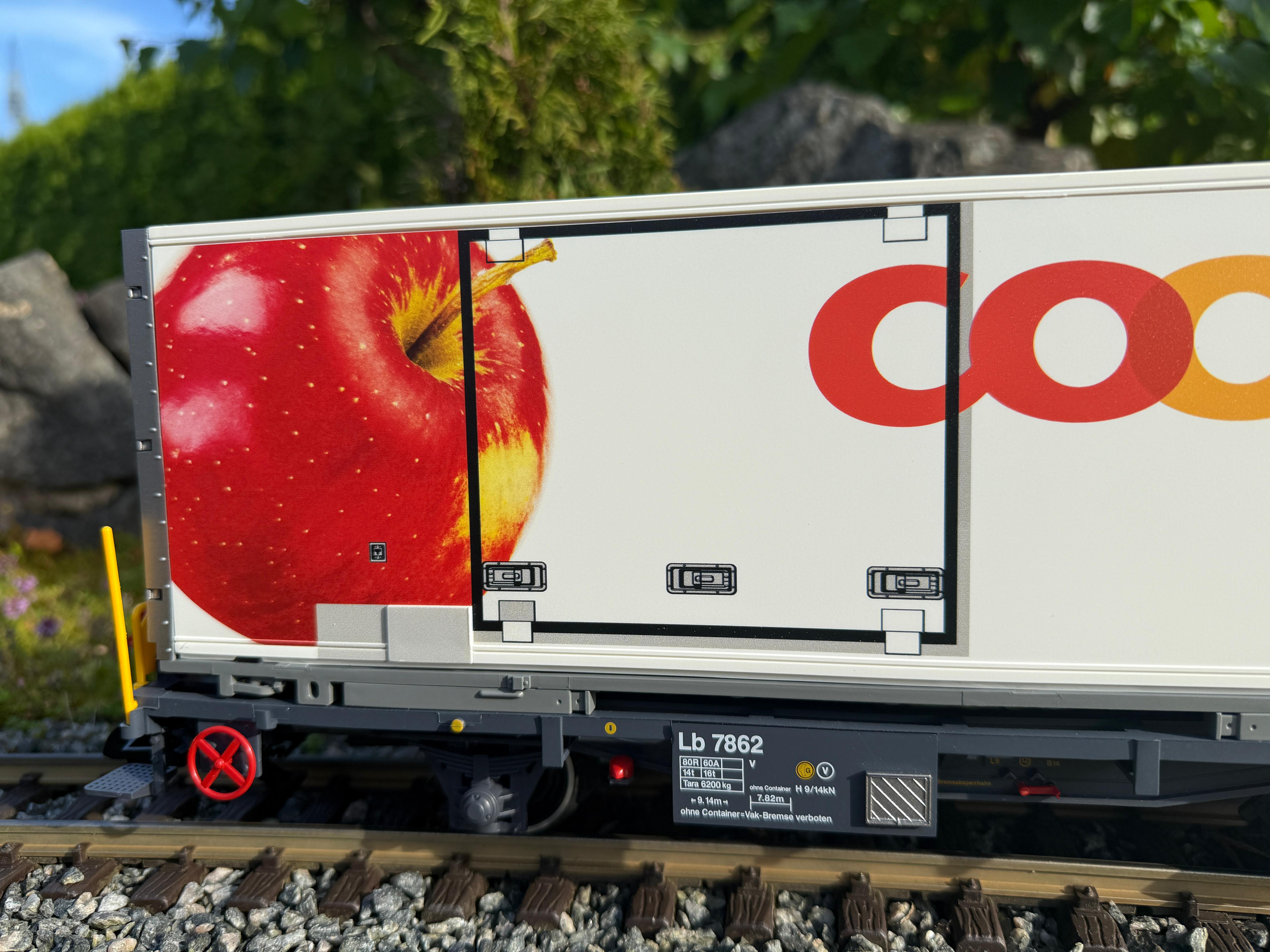 Großaufnahme vom Tragwerkwagen mit der Coop Wechselbrücke (Container) mit dem Apfel. LGB Art. Nr. 45887-01.
