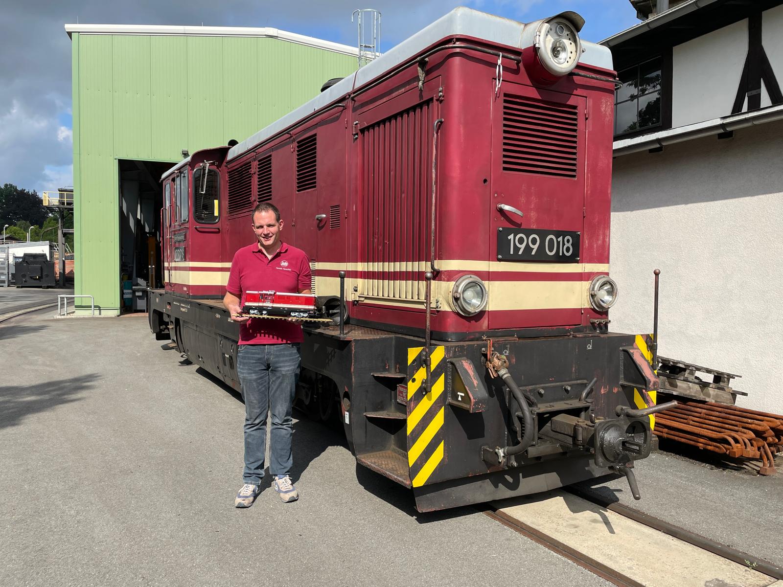 Hendrik hält das Modell der FAUR L45H von LGB für die Fotografen vor der Originallok in die Kamera.