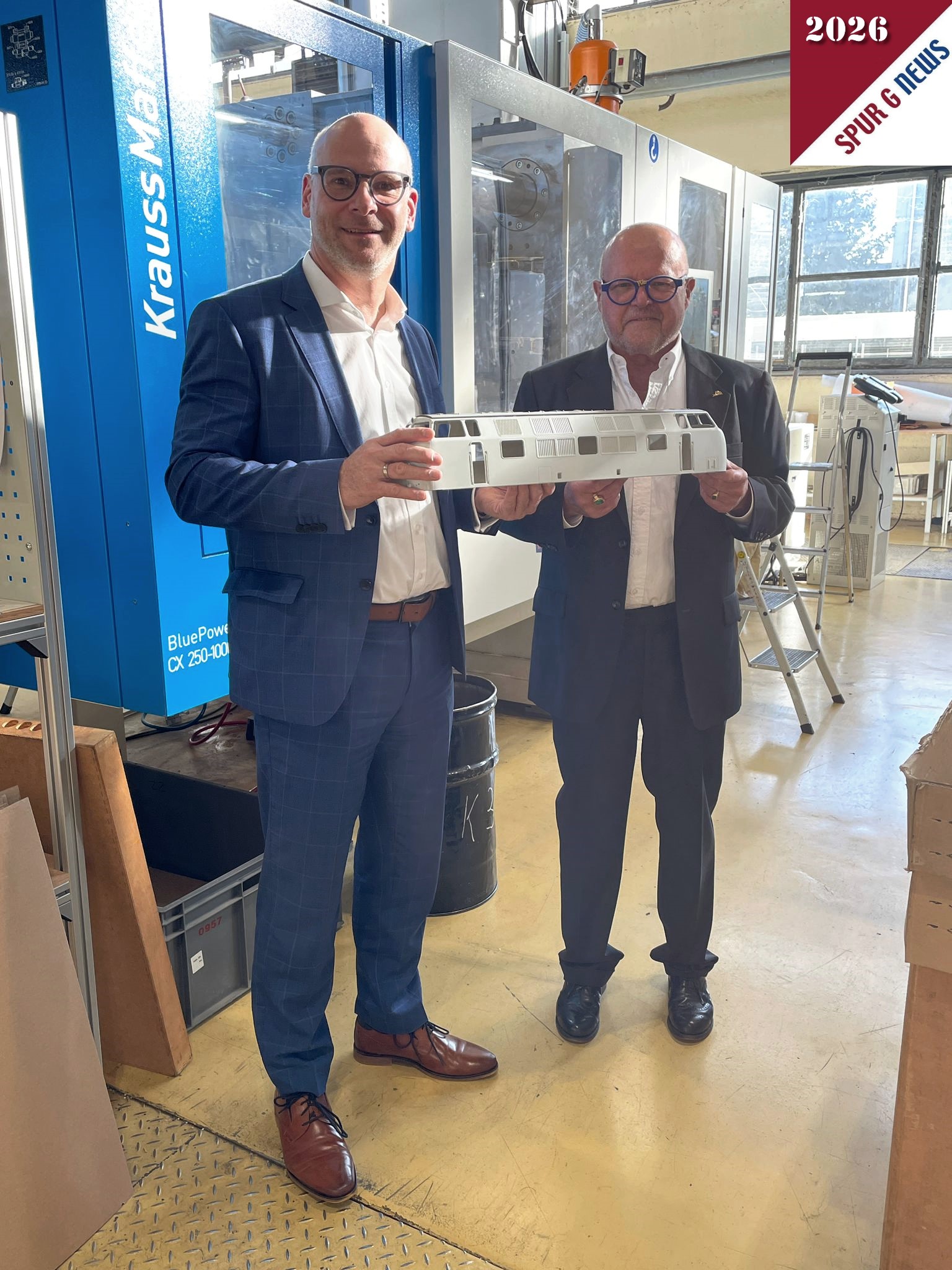 Herr Rainer Landwehr und Herr Dr. Ren� F. Wilfer pr�stenieren ein "frisch" gepresstes Geh�use einer V200 in der Produktion. Im Hintergrund die 2025 neu angeschafften Formenpressen von Krauss Maffei. 