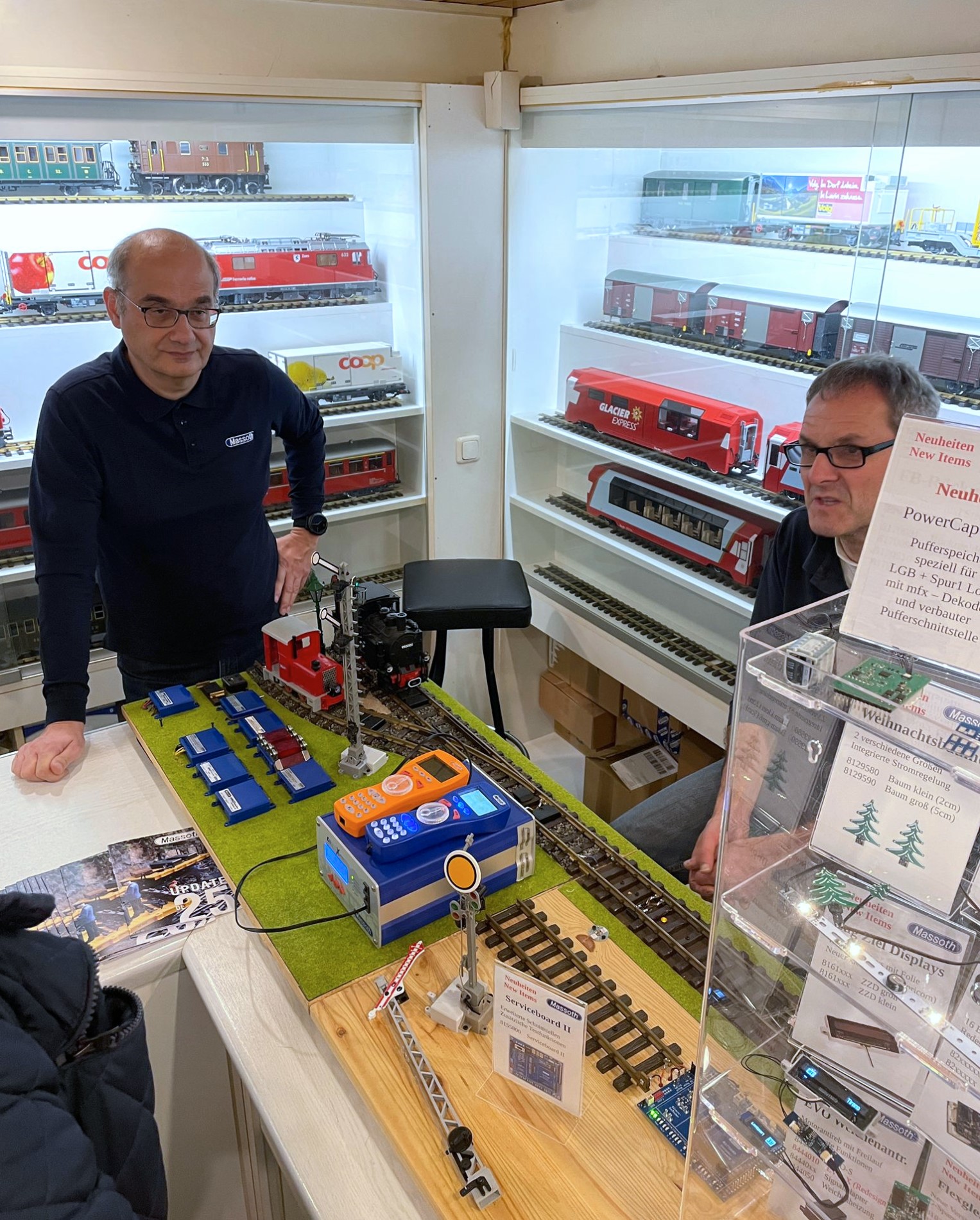 Frank Nller und Norbert Rosch waren mit Ihrem aktiven Vorfhrstand und den Neuheiten 2025 ebenfall im Modellbahn-Atelier Renken zu Gast. Hier konnten die Besucher sich ber den aktuellen Stand der Neuheiten informieren. Der in der Bildmitte sichtbare orange Handregler kommt in den nchsten Wochen in den Handel. Fr Harzfahrer ein "Must have". Viele Besucher hatten Fragen zu Decodern, Einstellungen der CVs, , Zurstteilen, Pufferspeicher und vieles mehr. Mancher Gast hatte gleich seine Lok mitgebracht und es konnten Einstellungen wieder "gerichtet" werden. Somit hat sich fr diese Gste der Besuch beim Fest im Oktober schon gelohnt. 