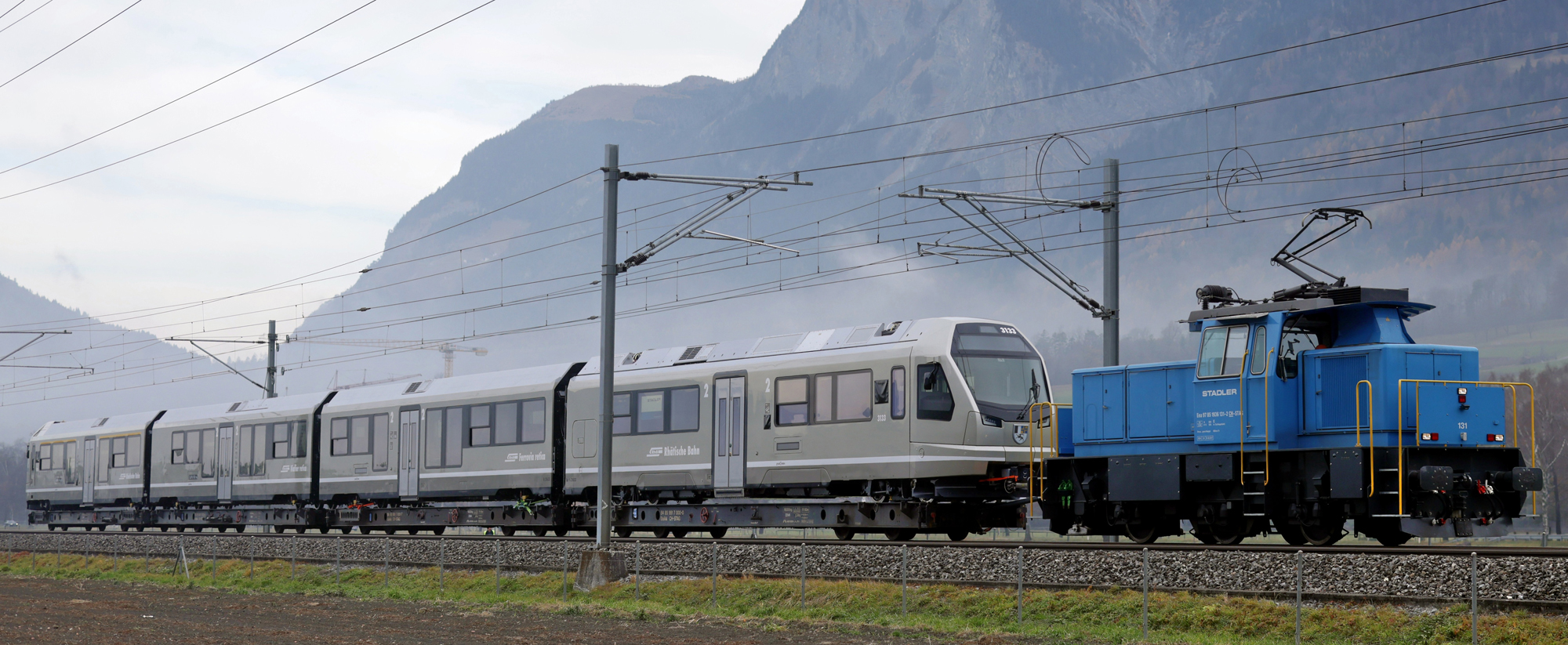 Foto: RhB - © Rhätische Bahn - Auf Rollwagen wurde der vierteilige Jubiläums Capricorn von Altenrhein aus den Stadler Werken nach Landquart zur Infrastrukturhalle der RhB transportiert. 