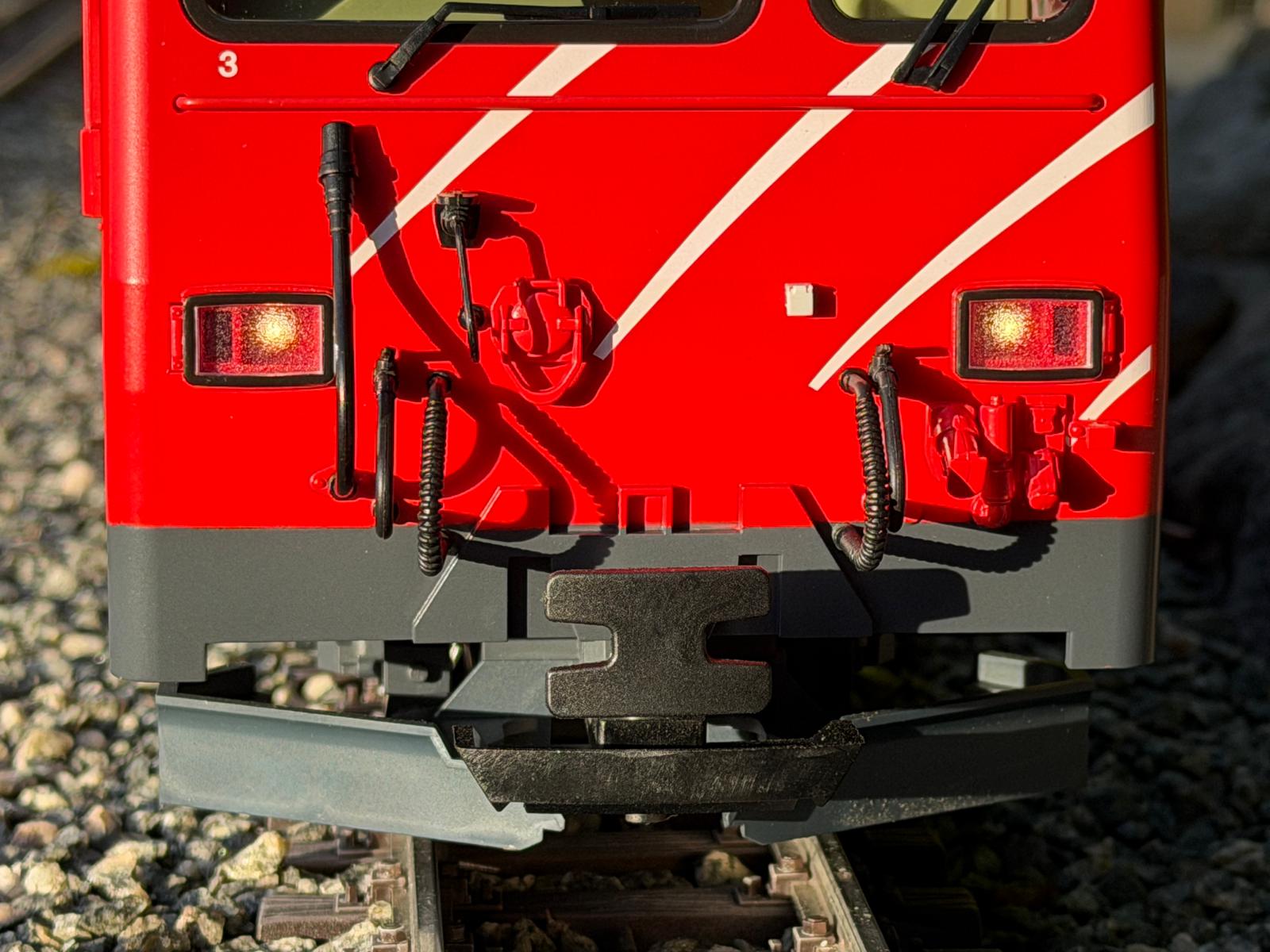 Teilansicht der Front der HGe 4/4 II MGB mit Kupplungen, Schläuchen, Steckdosen und dem Puffer.