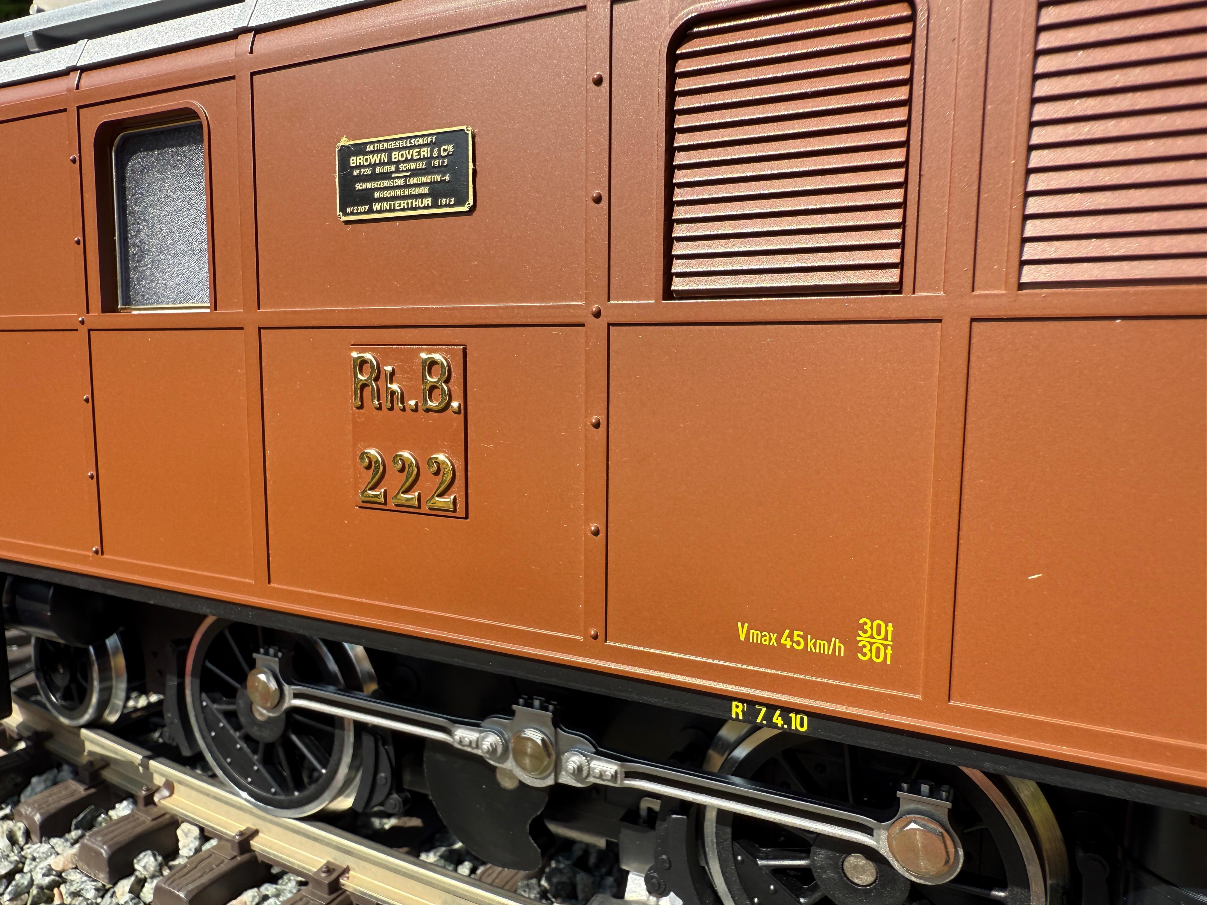 Das Modell der RhB Ge 2/4 (Art. Nr. 24451) von LGB ist ausgeliefert. Detailaufnahme der Seitenwand und des Gestänges. Das Herstellerschild ist erhaben angebracht und auf dem Schwarzen Untergrund steht in goldenen Buchstagen: Aktiengesellschaft Brown Boveri & Cie. Nr. 726 Baden Schweiz 1913. Schweizerische Lokomotiv und Maschinenfabrik Nr. 2307 Winterthur 1913. Das Typenschild ist mit dem alten Rh.B. Logo und der Nummer 222 angebracht.