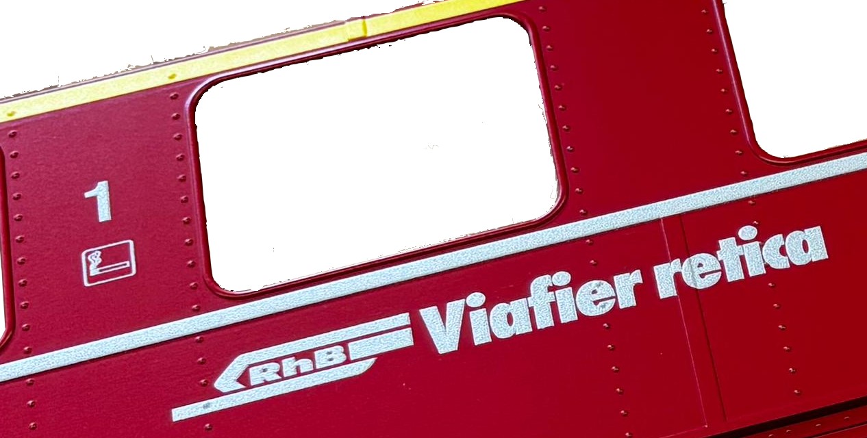 Bildausschnit: gelber 1. Klasse Streifen, Klasse 1 mit Raucher Piktogramm, Logo RhB und Viafier retica = Name der Rhätischen Bahn in rätoromaisch
