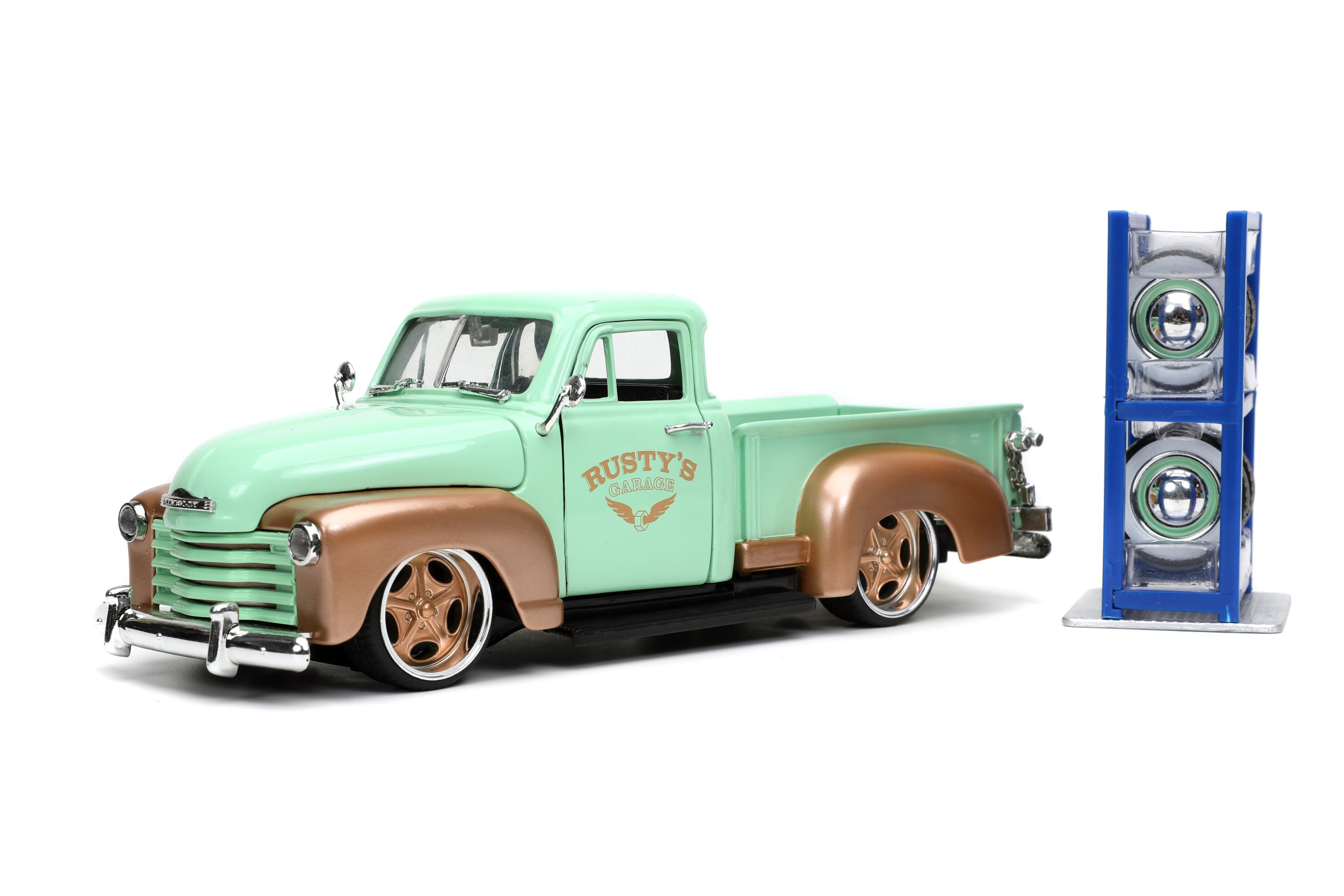 Modell eines Chevy Pick Up aus dem Jahr3 1953. Die von General Motors gebauten Pick Ups hatten an Vorne und hinten ausgestellte Kotflügel. Der mintgrüne Chevy ist mit dem kupferfarbenen LOGO RUSTY`S Garage, kupferfarbenen Kotflügeln und zwei Sätzen von Felgen mit Reifen hergestellt. Die "gepimpten" Niederquerschnittsreifen mit kupferfarbenen Felgen können gegen die klassischen Felgen mit Weißwandreifen und Chromradkappen ausgetauscht werden. Ein Reifenregal in blau liegt der Packung bei. Schraubendreher ist für die Montage ebenfalls im Lieferumfang enthalten. 