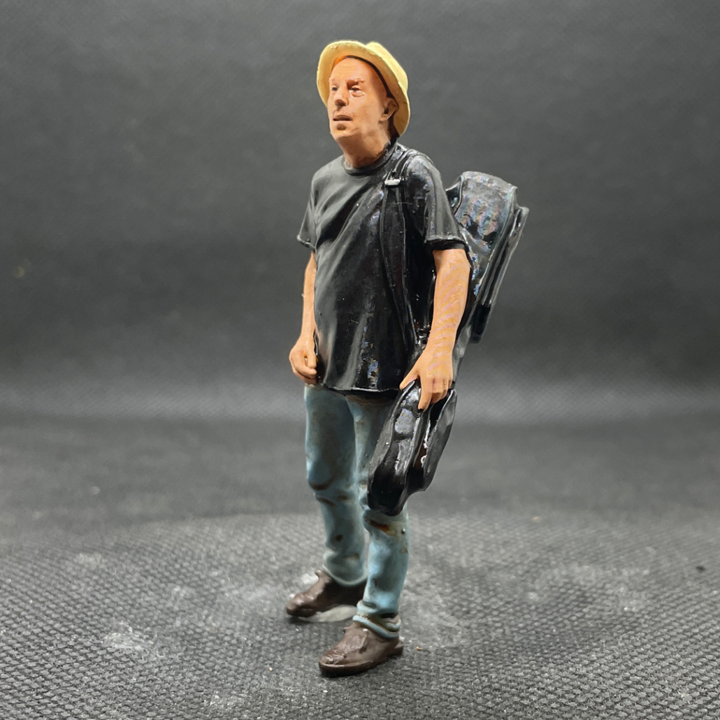 Figur: Jensi: Die Gitarre noch eingepackt in die Schutzhülle kommt er zu seinen anderen Musikern.