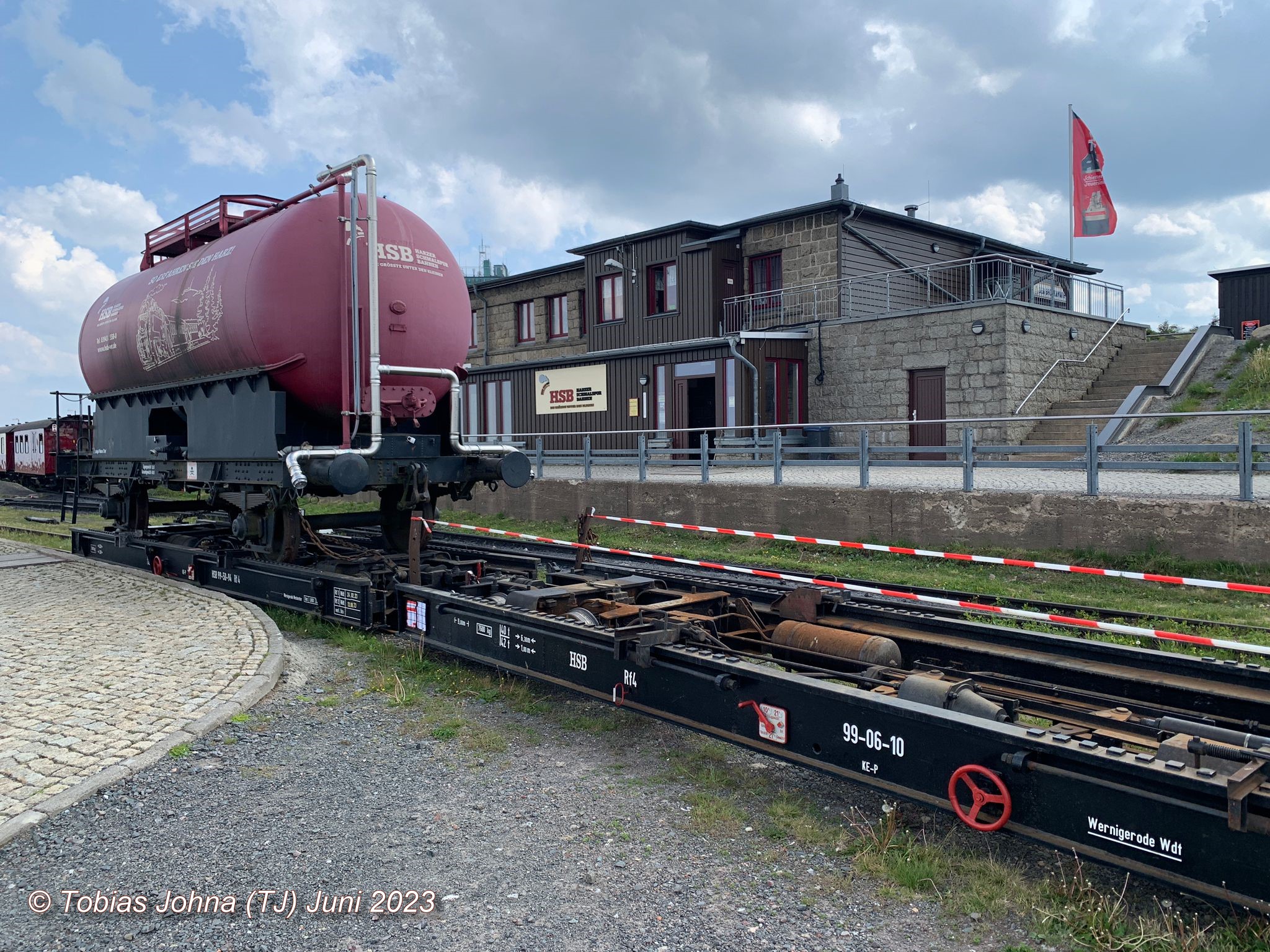 Die beiden Rollwagen der HSB vorne mit dem HSB Löschwasserwagen beladen: 99-50-54 und ohne Beladung 99-06-10. Blick zum Bahnhof Brocken in dem auch die Gaststätte untergebracht ist. 