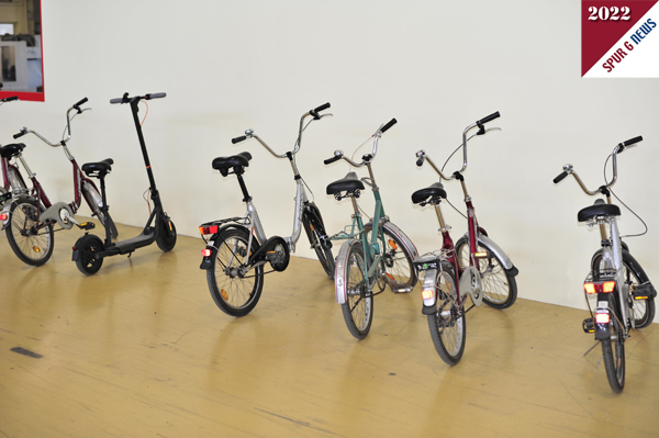 Wie im Januar schon berichtet, stehen auch im Juni 2022 die Fortbewegungsmittel in Form von Fahrrädern und dem E-Scooter von Herrn Dr. Wilfer, vor dem Werkzeugbau in der Spritzgusshalle. am TOFT sind die Fahrräder nicht zu sehen. 