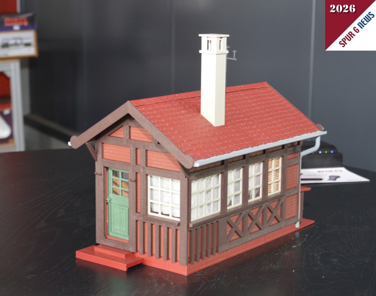 Das Bahnw�rterhaus - Art. Nr. 65002 - konnten wir auf dem Pr�sentiertisch fotografieren. Link der Eingang des Hauses und rechts der Hinterhof mit dem gestapelten Holz unter der kleinen �berdachung. Sicherlich ragt der Kamin im Vorbild des Bahnw�rterhauses auch so in die H�he. Im Prospekt ist das Fachwerk wei� abgebildet. Hier beim Start in die Gartenbahnsaison sind es Klinkersteine die zwischen den aufgesetzten Balken eingebaut sind. Auch die Dachrinnen sind hier im Muster grau dargestellt. Im Prospekt gr�n. Wir werden erneut dar�ber berichten. 