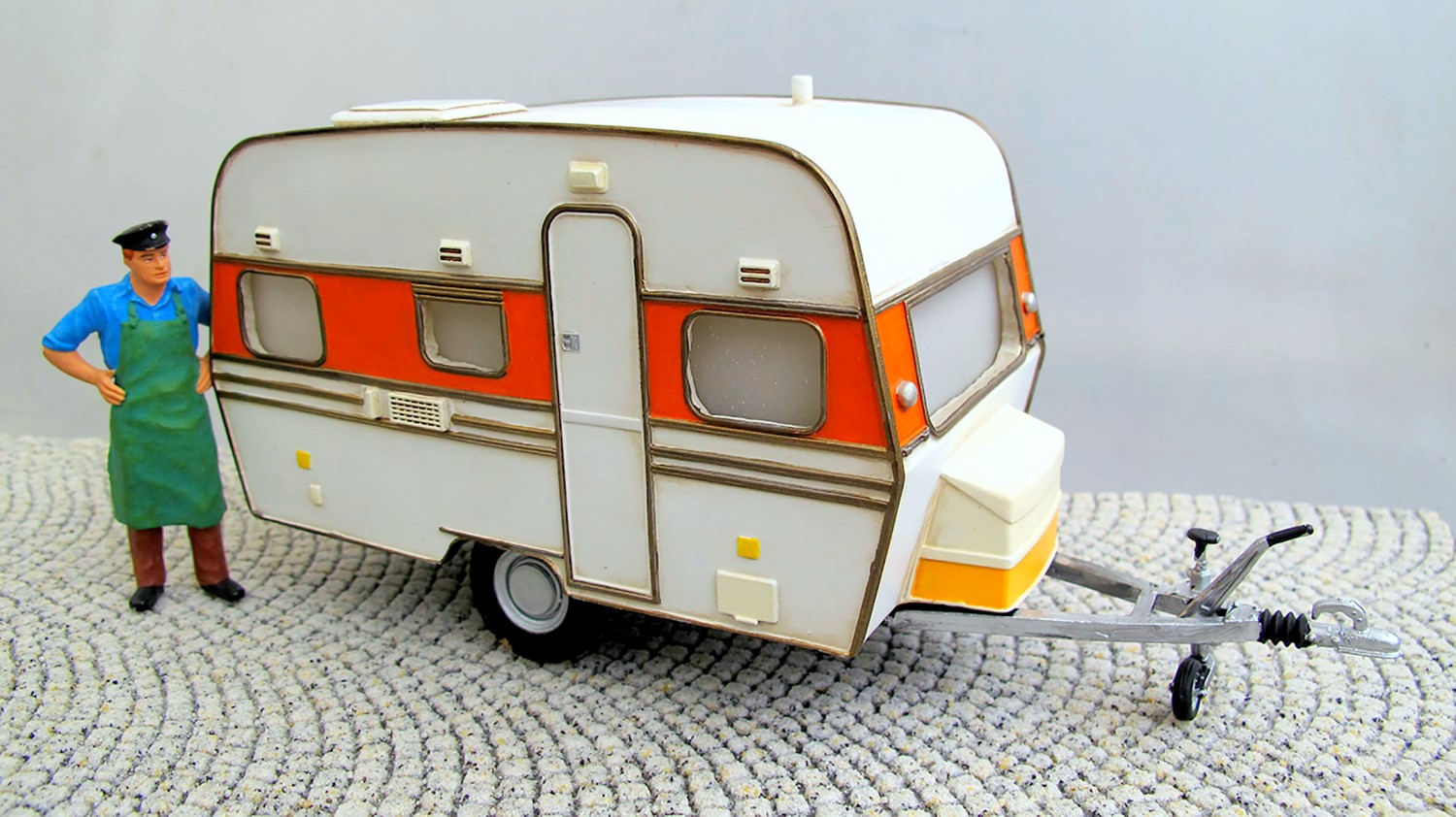 Das Standmodell ist nach dem Vorbild eines Wohnwagens aus den 60ziger Jahren nachempfunden und passt herrlich in die Dampflokzeit. Das aus High-Grad-Resin gefertigte Modell ist fein detailliert und leicht gealtert, passend zu einer Campingszene.