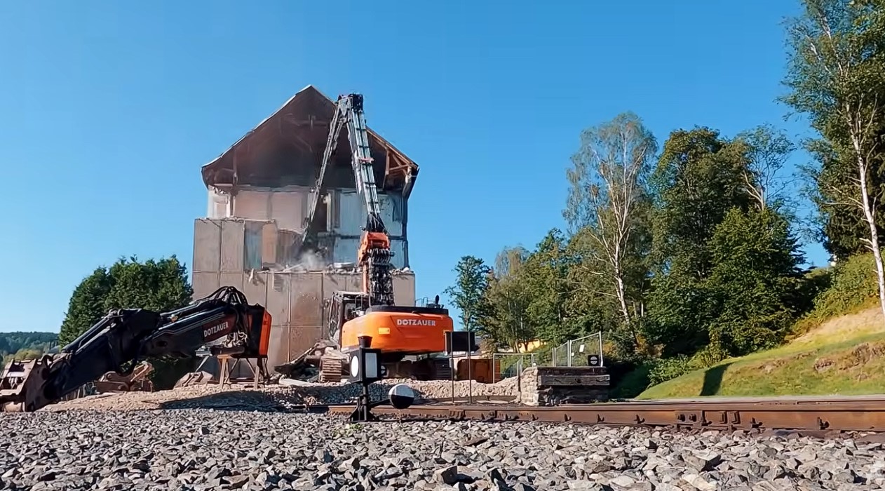 Am 3. August 2026 hat nun endlich der Abriss des alten Wohnblocks mitten auf dem Bahnhofsgel�nde in J�hstadt begonnen. Ein historischer Tag f�r die IG Pre�nitztalbahn. Wir waren nat�rlich f�r euch beim ersten Baggerbiss dabei.