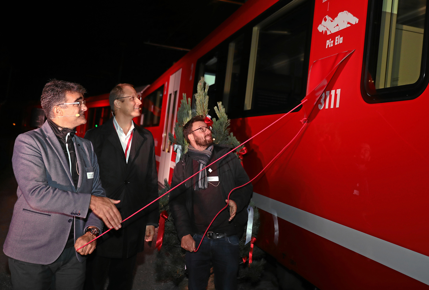 Foto: RhB -  Rhtische Bahn: Zugtaufe mit Marcus Caduff (links i. Bild), Luzi C. Schutz (rechts i. Bild) und Dr. Renato Fasciati (Mitte). 
